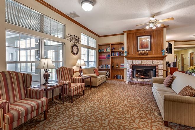 A cozy living room featuring comfortable seating, a fireplace, and bookshelves.