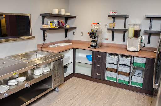 A well-organized and modern commercial kitchen with wooden countertops, shelves for storage, and essential appliances.