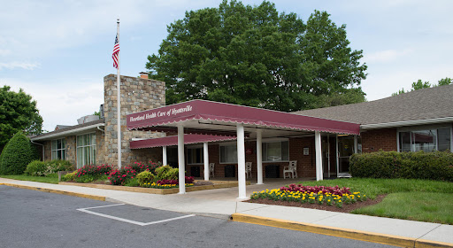 The welcoming entrance of a residential facility, adorned with landscaping and an American flag.