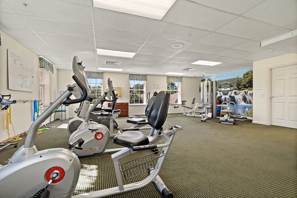 A well-lit gym with various exercise equipment including treadmills and stationary bikes.
