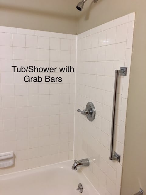 Accessible bathroom with tub/shower and grab bars for safety.