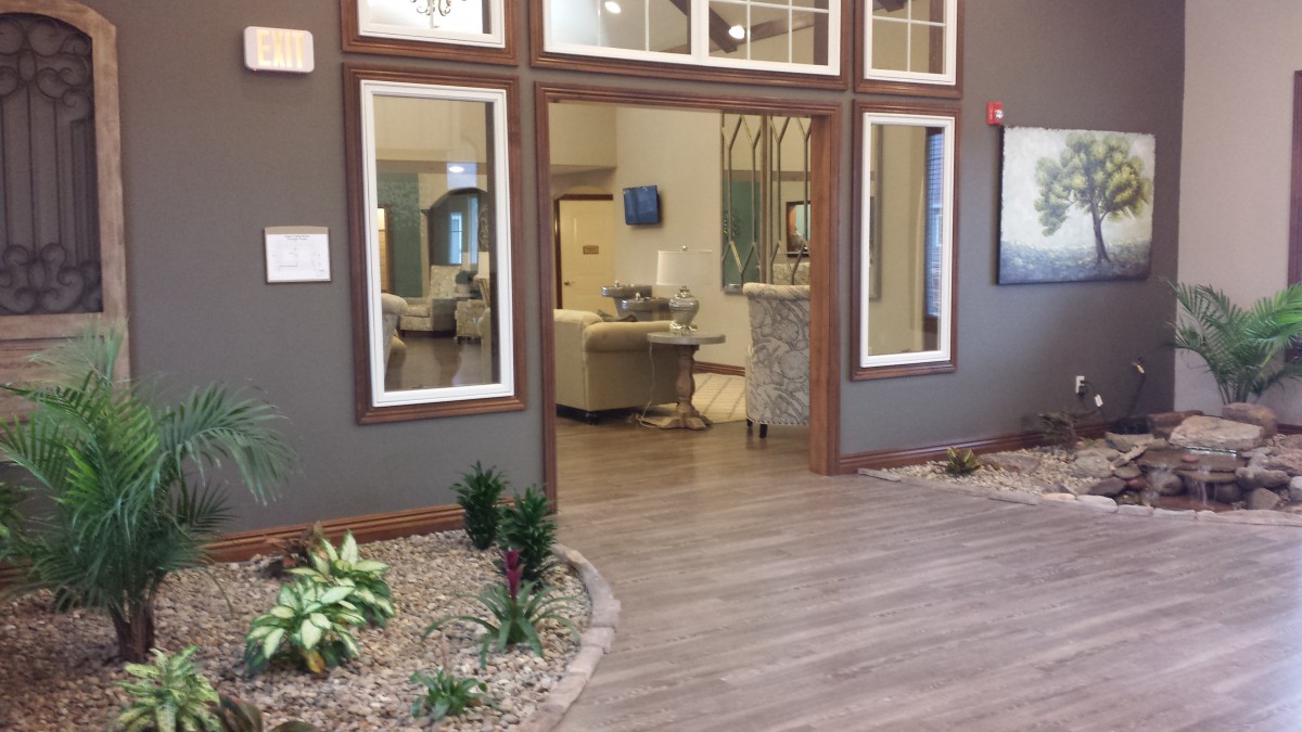 A modern lobby with wood flooring, featuring comfortable seating and indoor plants for a welcoming atmosphere.