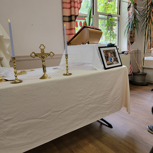 An altar setup with candles and a cross, featuring a framed photograph.