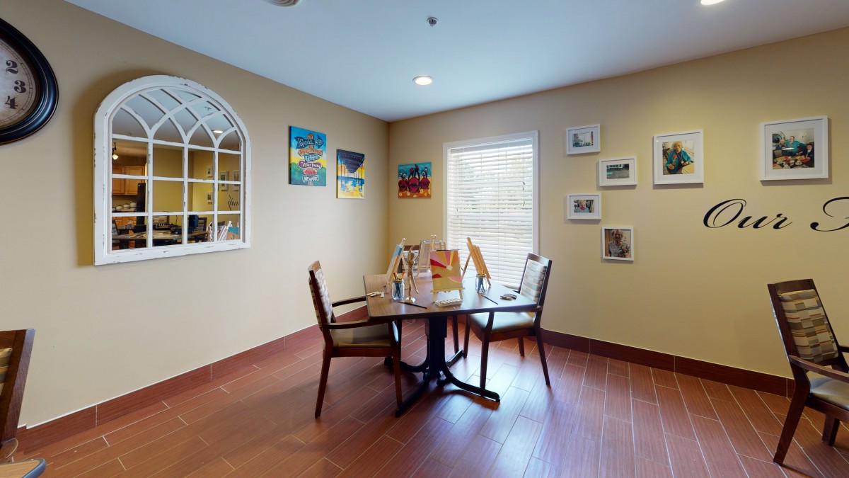A cozy dining area with a round table, chairs, and colorful artwork on the walls.