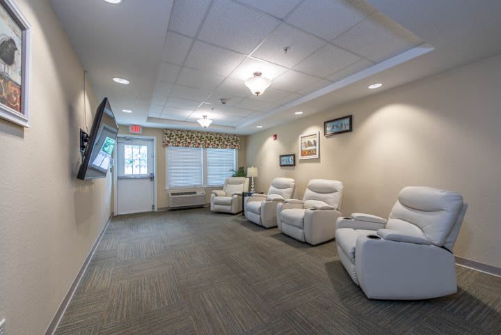 A cozy waiting room with comfortable recliners and a wall-mounted television.