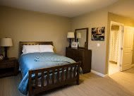 A cozy bedroom with a neatly made bed, dresser, and mirror.