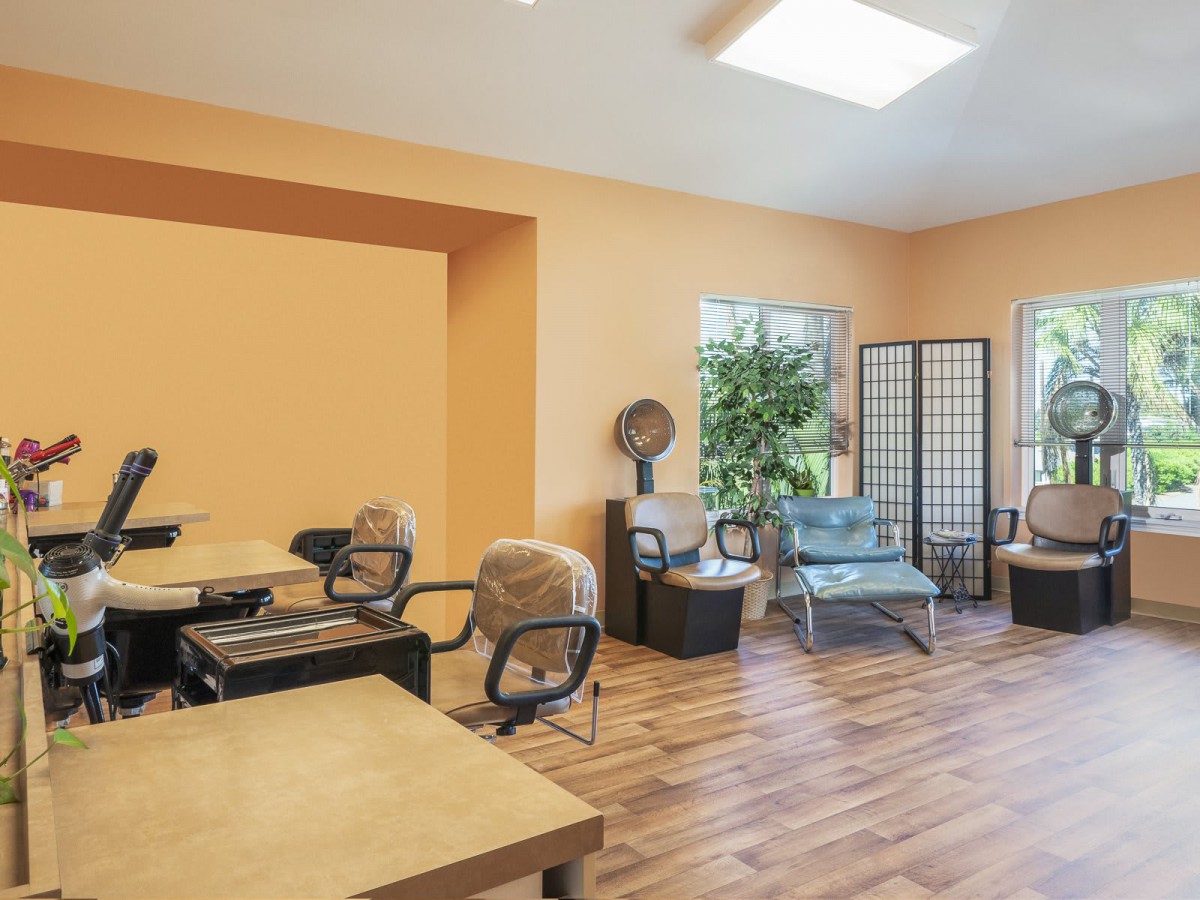 Modern salon interior with chairs, desks, and bright lighting.