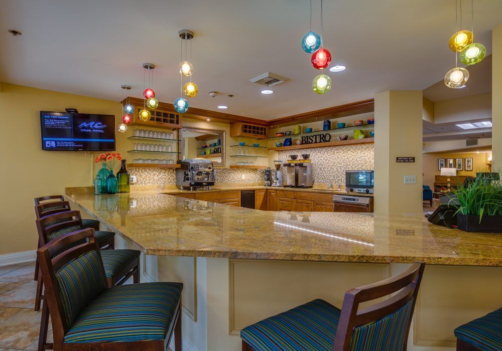 A cozy bar interior featuring a sleek counter with colorful pendant lights.