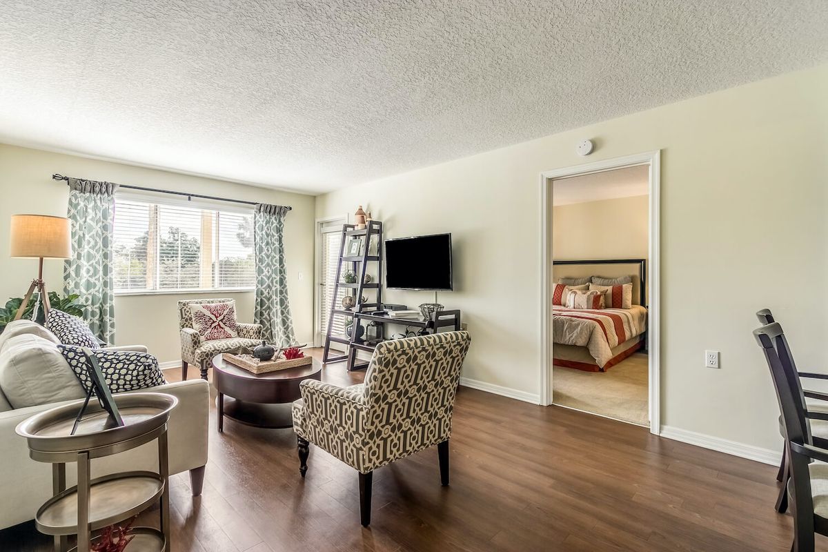 A cozy living room with stylish furniture and a view into a bedroom.