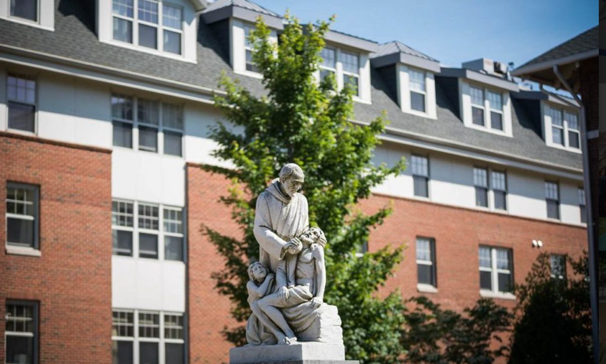 A statue in front of a building with large windows and trees nearby.