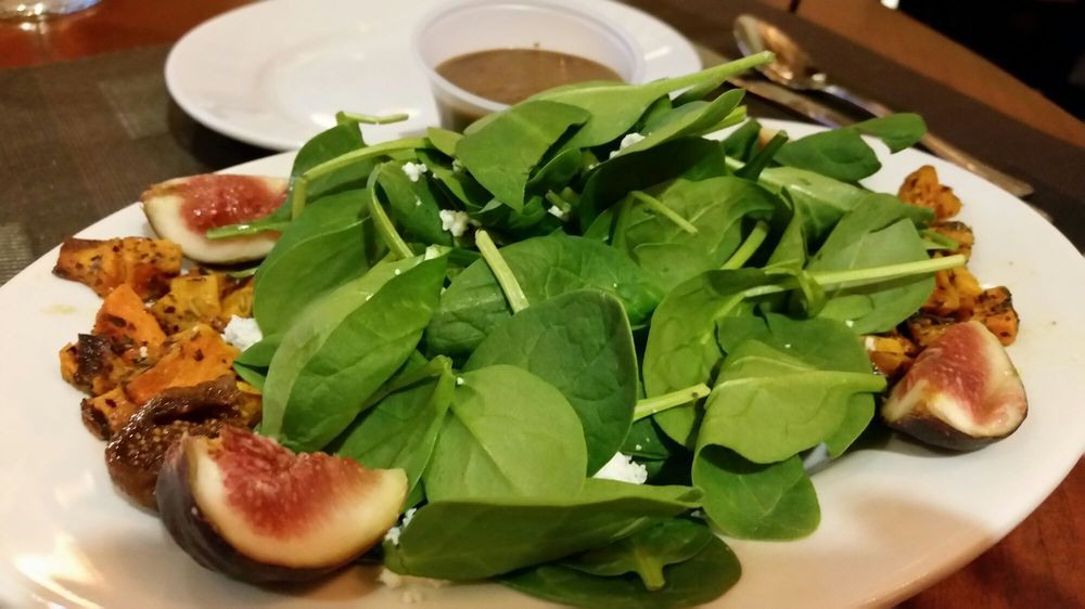 A fresh spinach salad with figs and dressing.