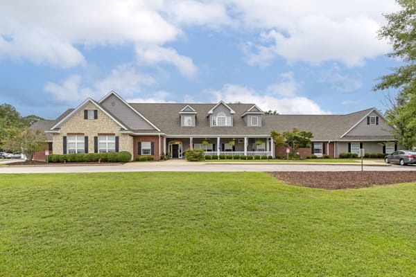 A large suburban house with a well-maintained lawn under a partly cloudy sky.