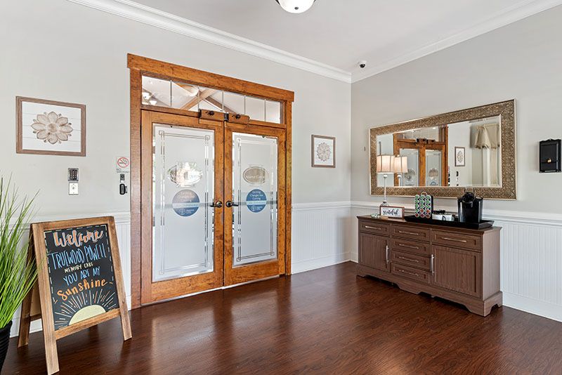 A welcoming entrance with wooden double doors and a mirror, complemented by elegant decor.