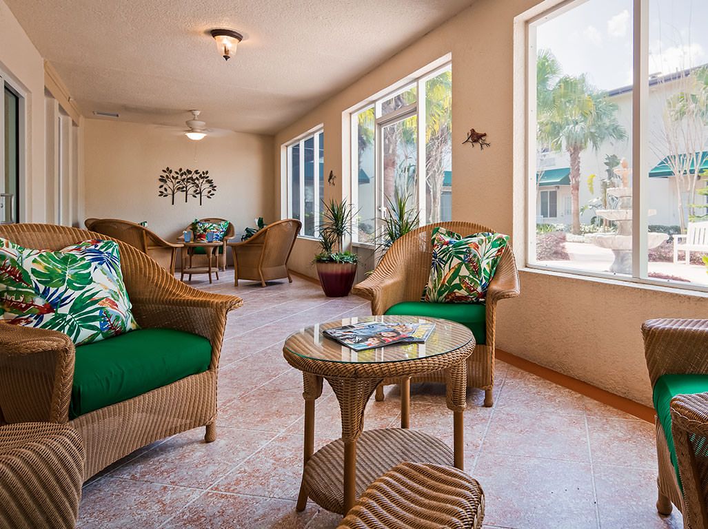 A cozy living room with wicker furniture and large windows letting in natural light.