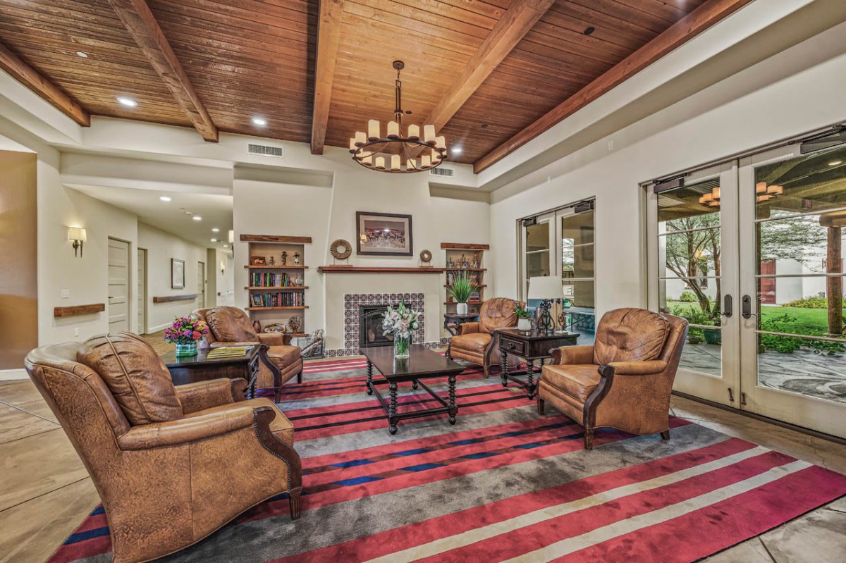 A spacious living room with leather chairs, a fireplace, and a wooden ceiling.
