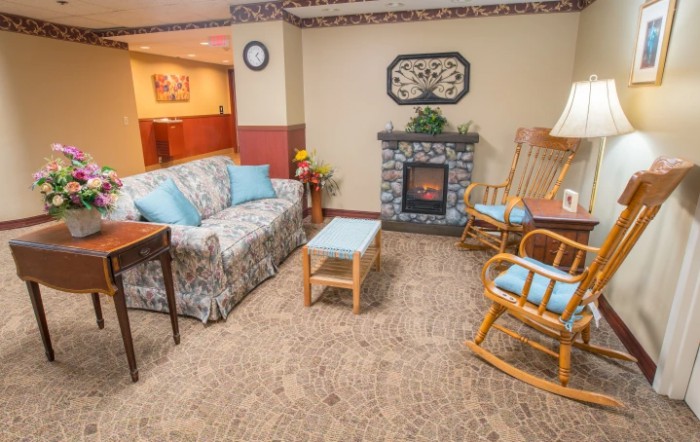 Cozy living room with a floral couch, rocking chairs, and a fireplace.
