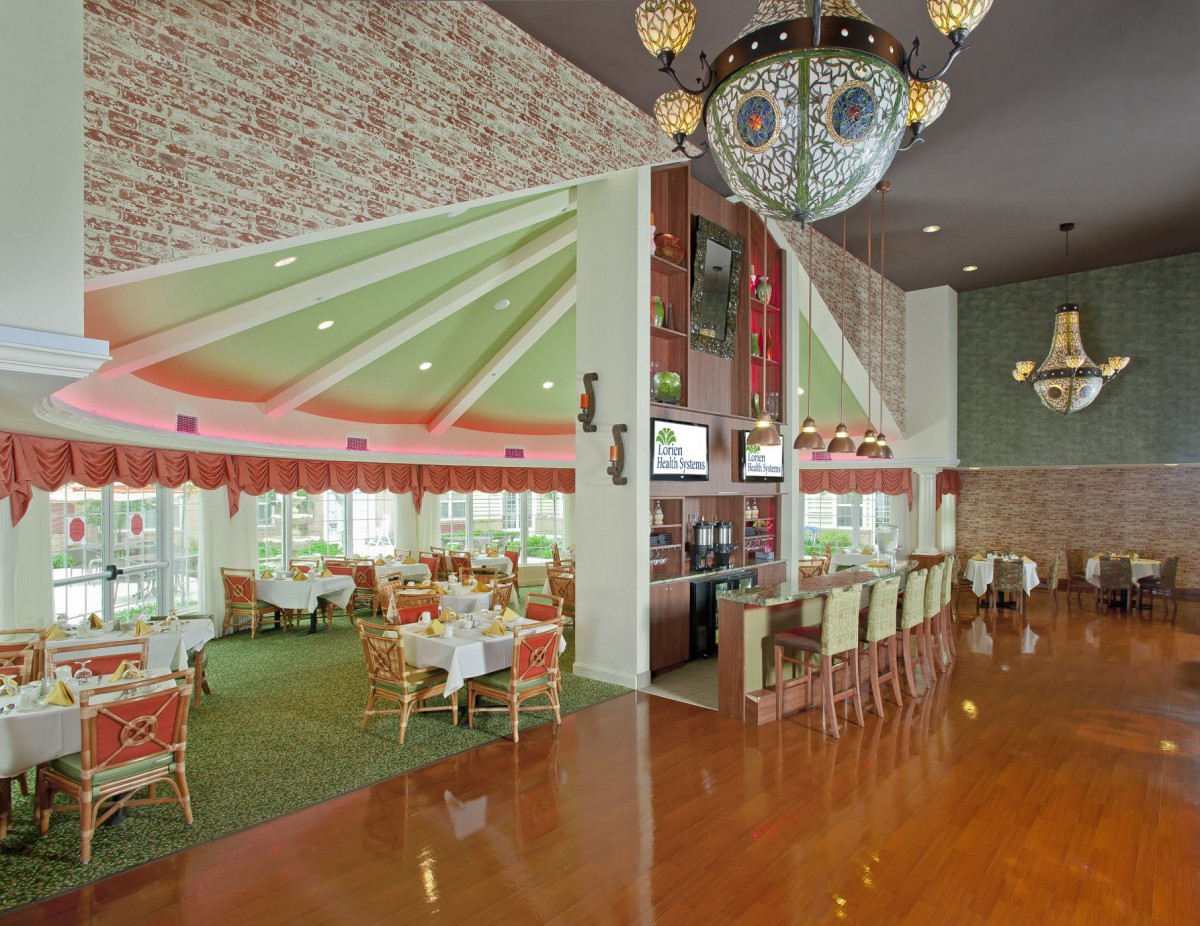 A spacious restaurant interior featuring a bar area and elegant chandeliers.