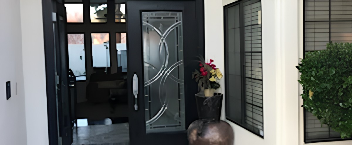 A modern entrance with a glass-designed door and decorative potted plants.