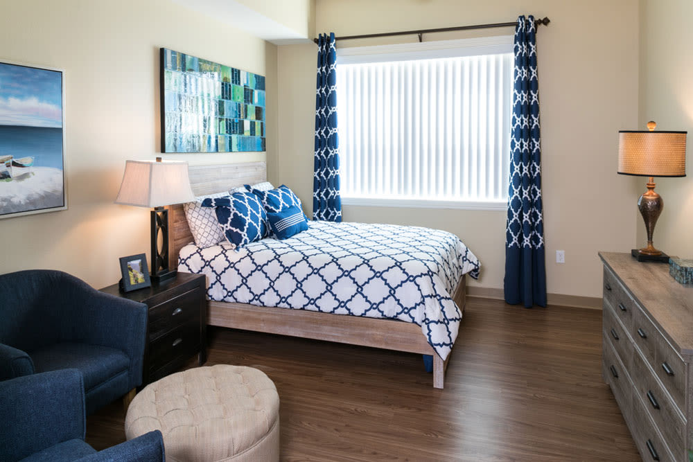 A modern bedroom featuring blue and white decor with patterned bedding and curtains, complemented by a wooden floor.