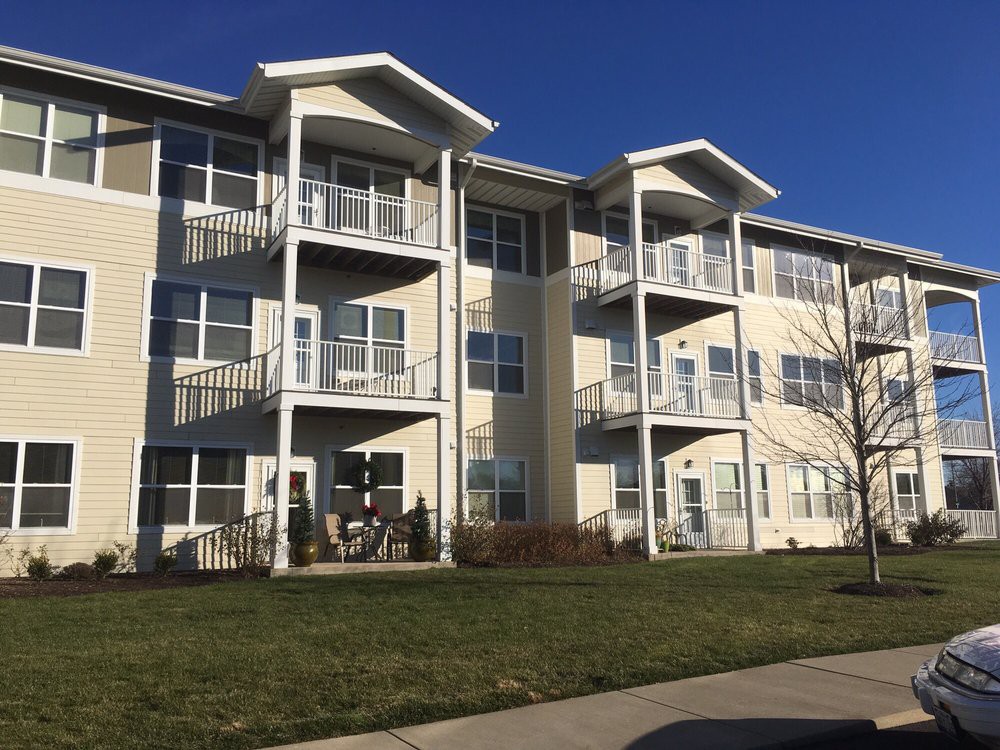 A modern three-story apartment building with balconies under a clear blue sky.