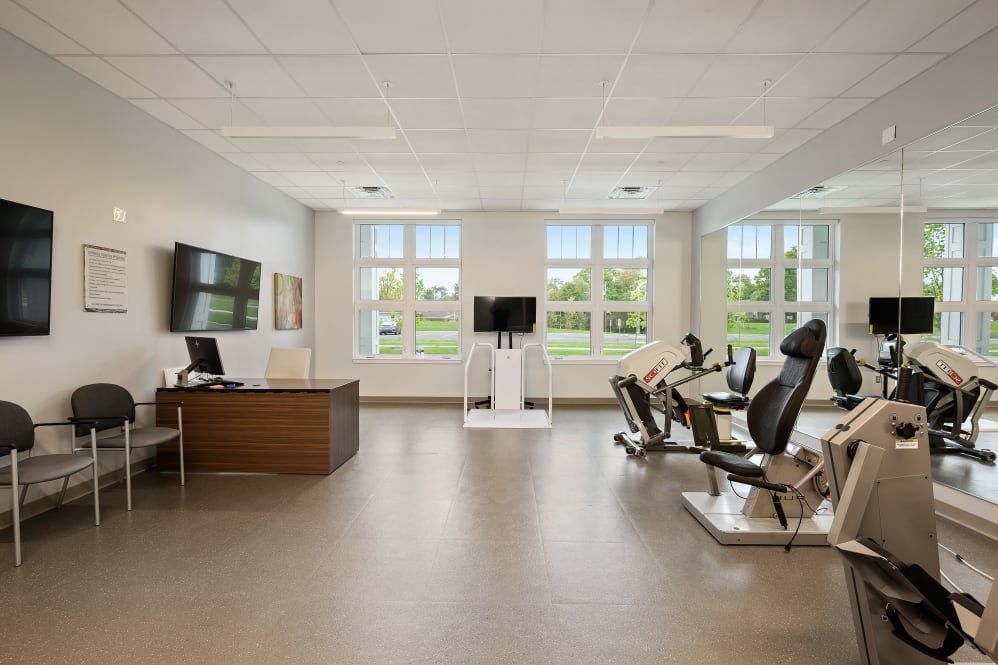 A modern office space with desks, chairs, and large windows providing natural light.