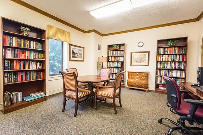 Cozy library reading room with bookshelves and a table with chairs.