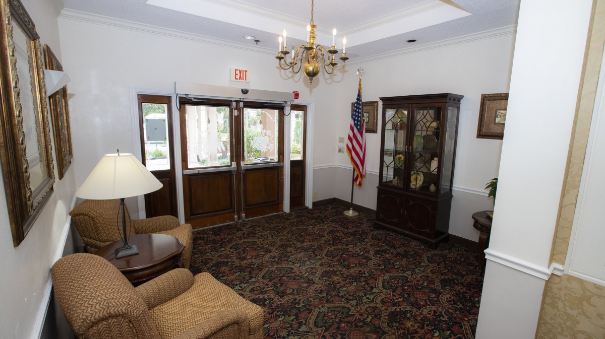An elegant lobby entrance featuring a chandelier, an American flag, a display cabinet, and comfortable seating.