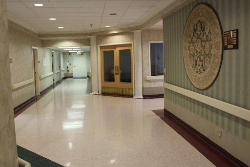 A well-lit hallway in a hospital featuring smooth flooring and decorative walls.