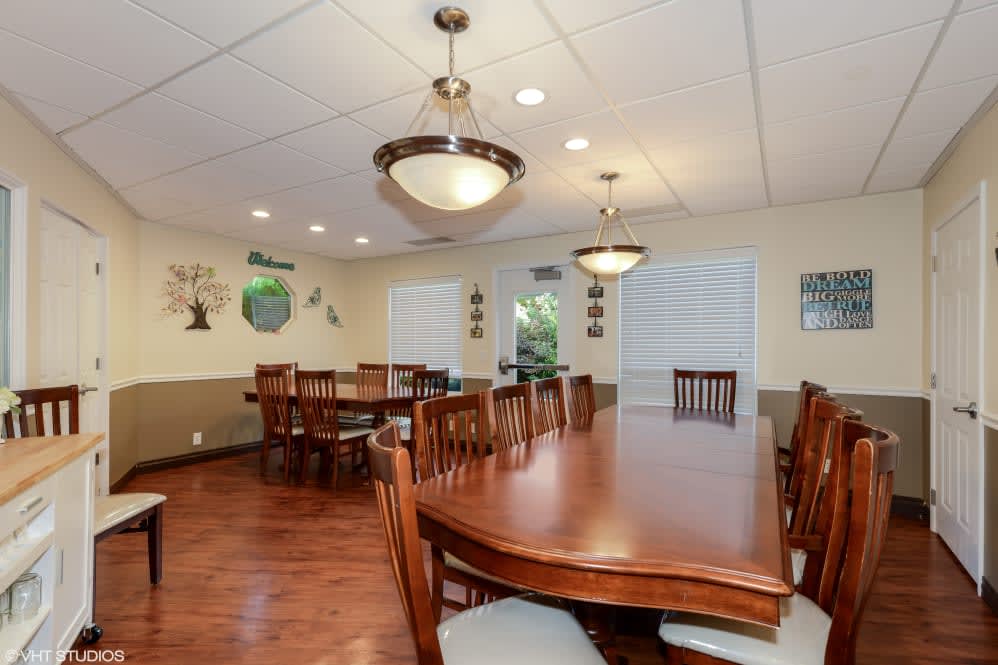 A spacious dining room with wooden tables and chairs, well-lit with modern ceiling lights.