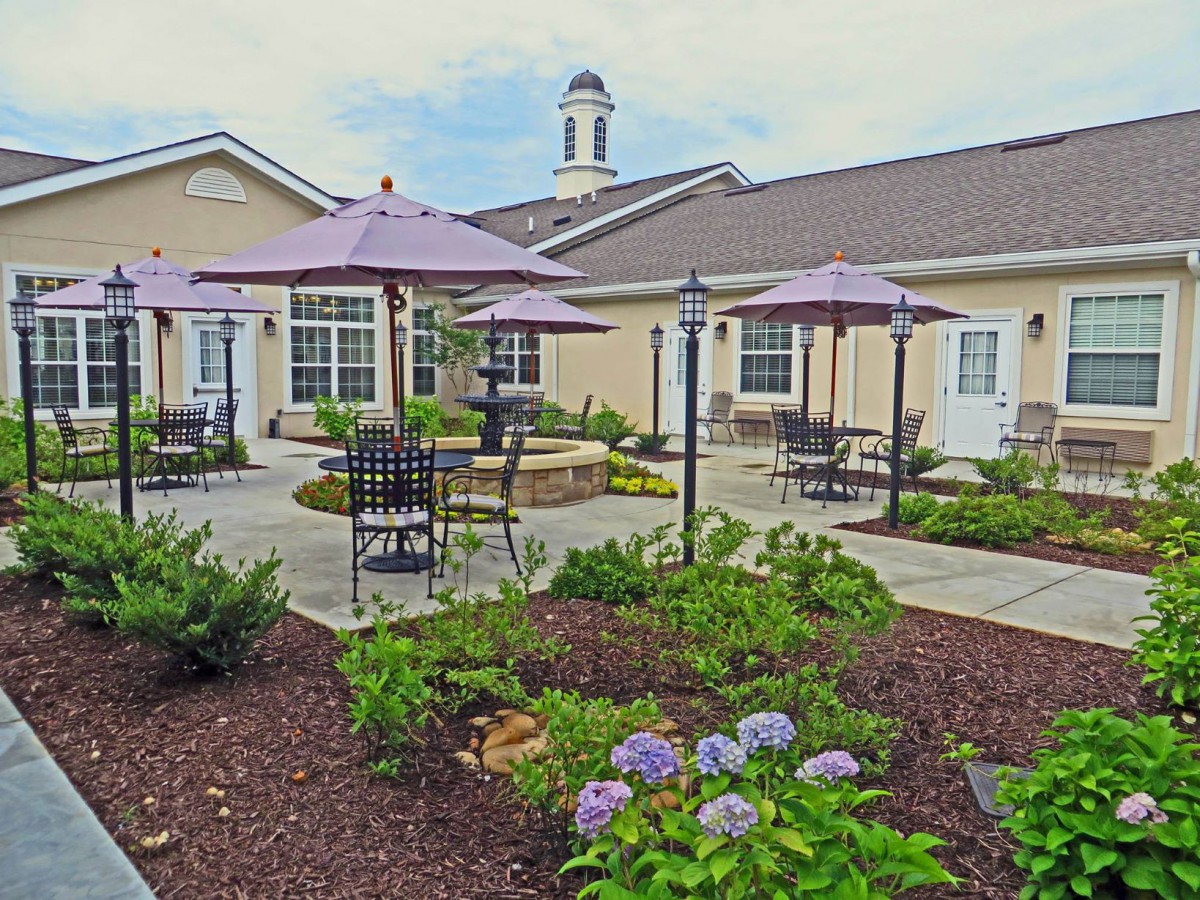 A well-maintained garden patio area with outdoor seating and umbrellas, surrounded by vibrant flowers.