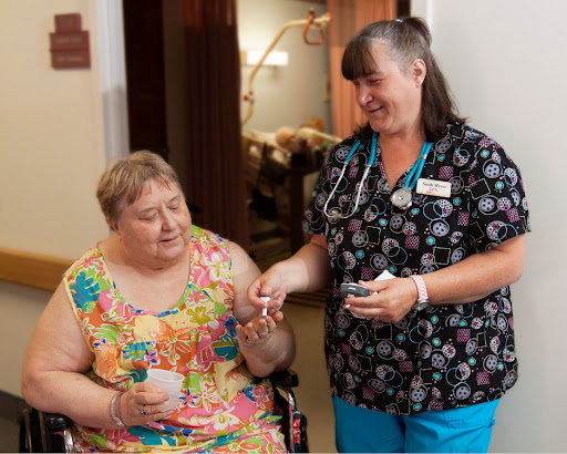 A nurse providing medication assistance to a patient in a caring environment.