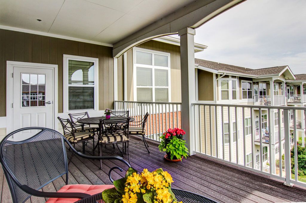 A cozy balcony with outdoor seating and colorful flowers.