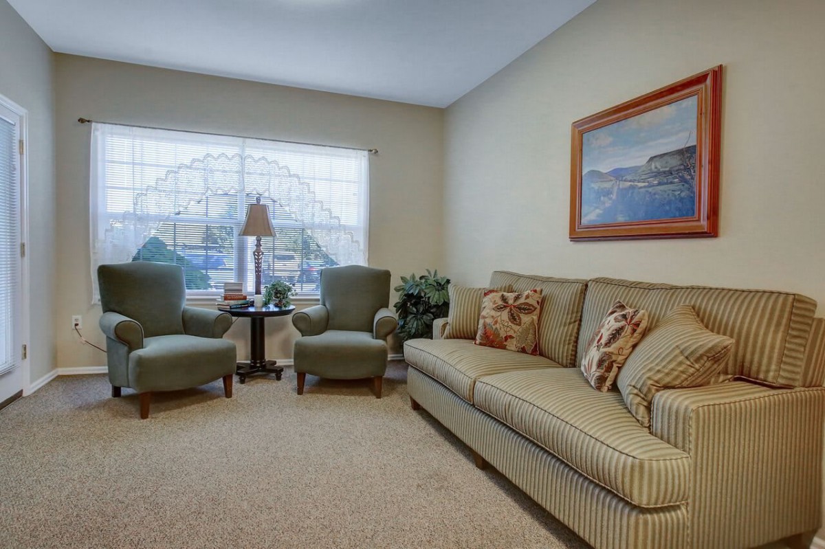 A cozy living room with a sofa, two chairs, and a large window.