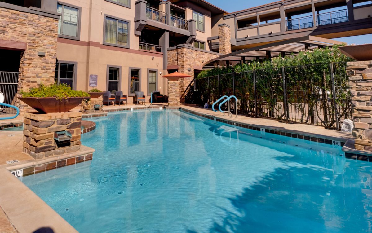 A serene swimming pool area within an apartment complex on a sunny day.