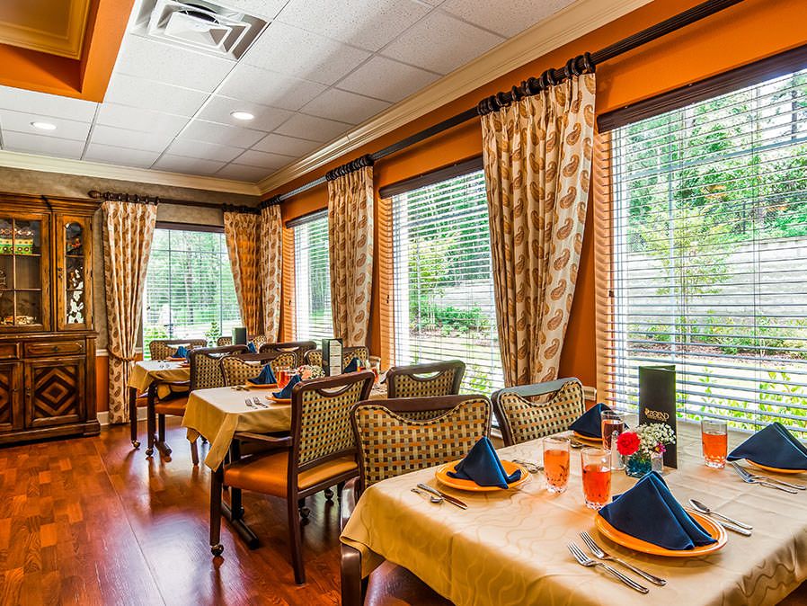 A beautifully arranged dining room with elegant table settings and large windows allowing natural light.