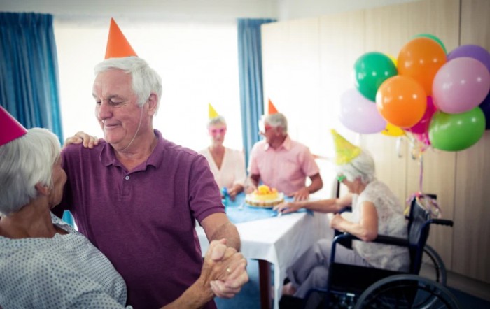A group of seniors celebrating a birthday party with colorful hats and balloons.