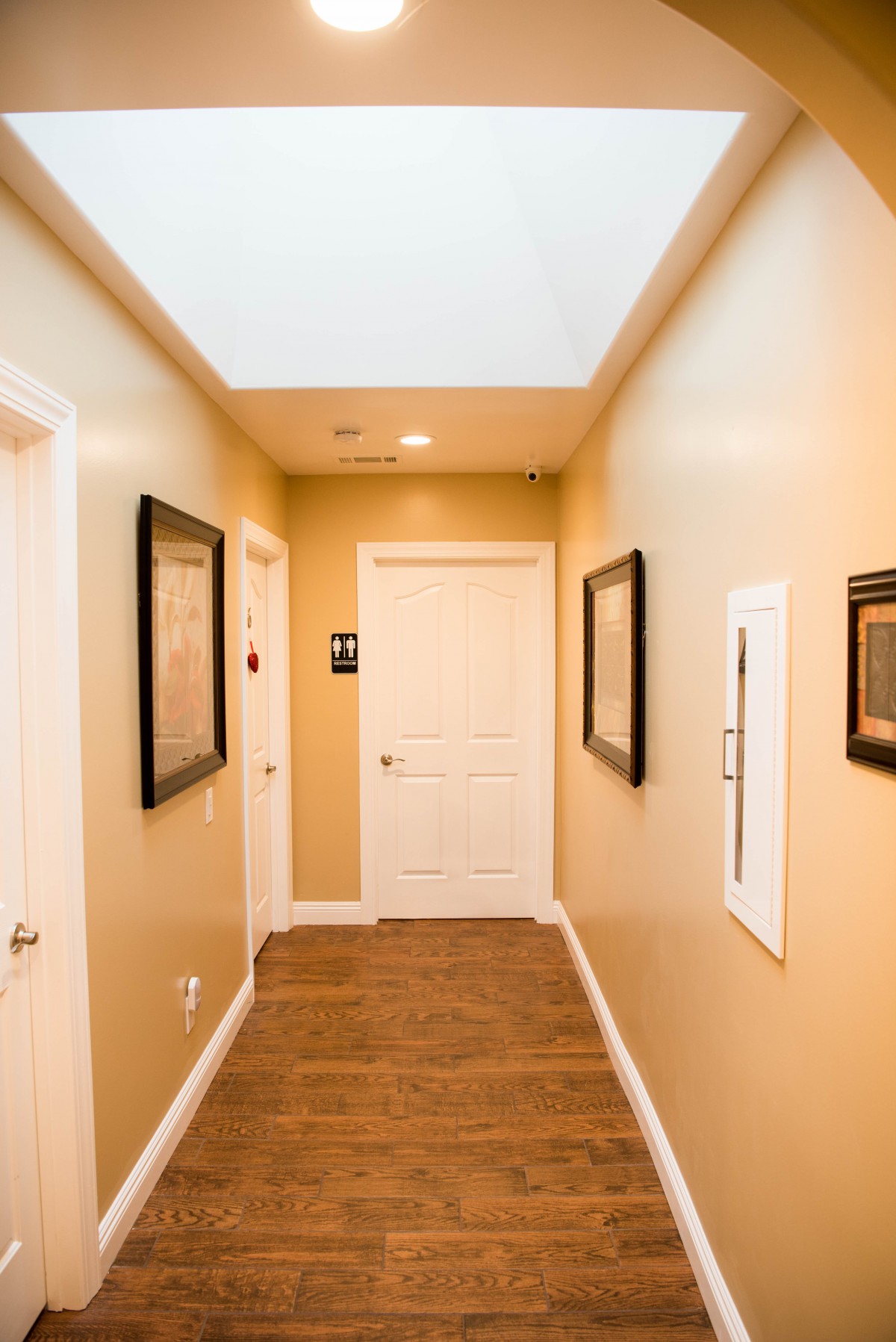 A well-lit hallway featuring framed art and multiple doors.