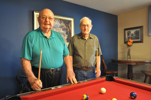 Two friends enjoying a game of billiards together.