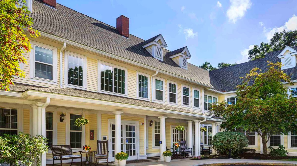 A large residential house with a porch and columns, surrounded by a garden.