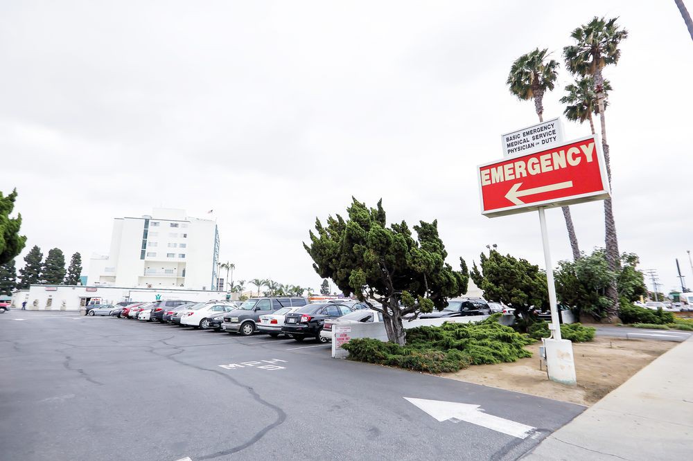 A hospital parking lot with an emergency sign pointing towards the entrance.