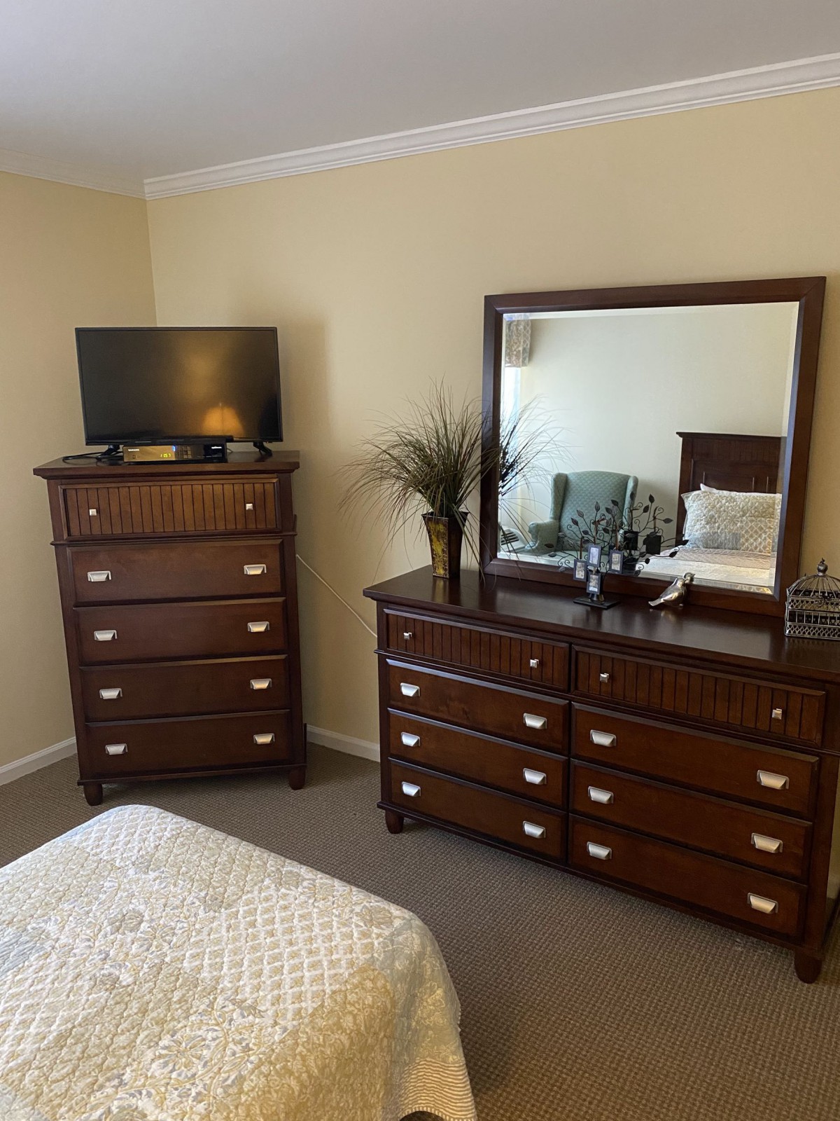 A cozy bedroom setup featuring a dresser with a mirror and a television atop another drawer unit.