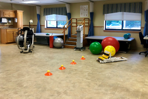 A physical therapy room equipped with exercise balls, cones for agility training, and various fitness equipment.