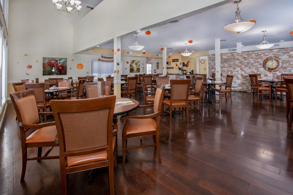 A spacious dining area with neatly arranged tables and chairs, featuring a wooden floor and elegant decor.