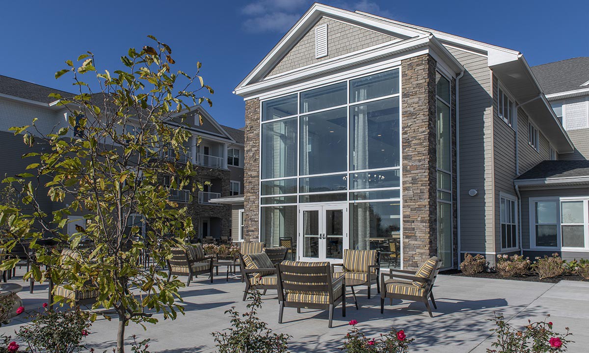 A modern building with large windows and outdoor seating on a sunny day.