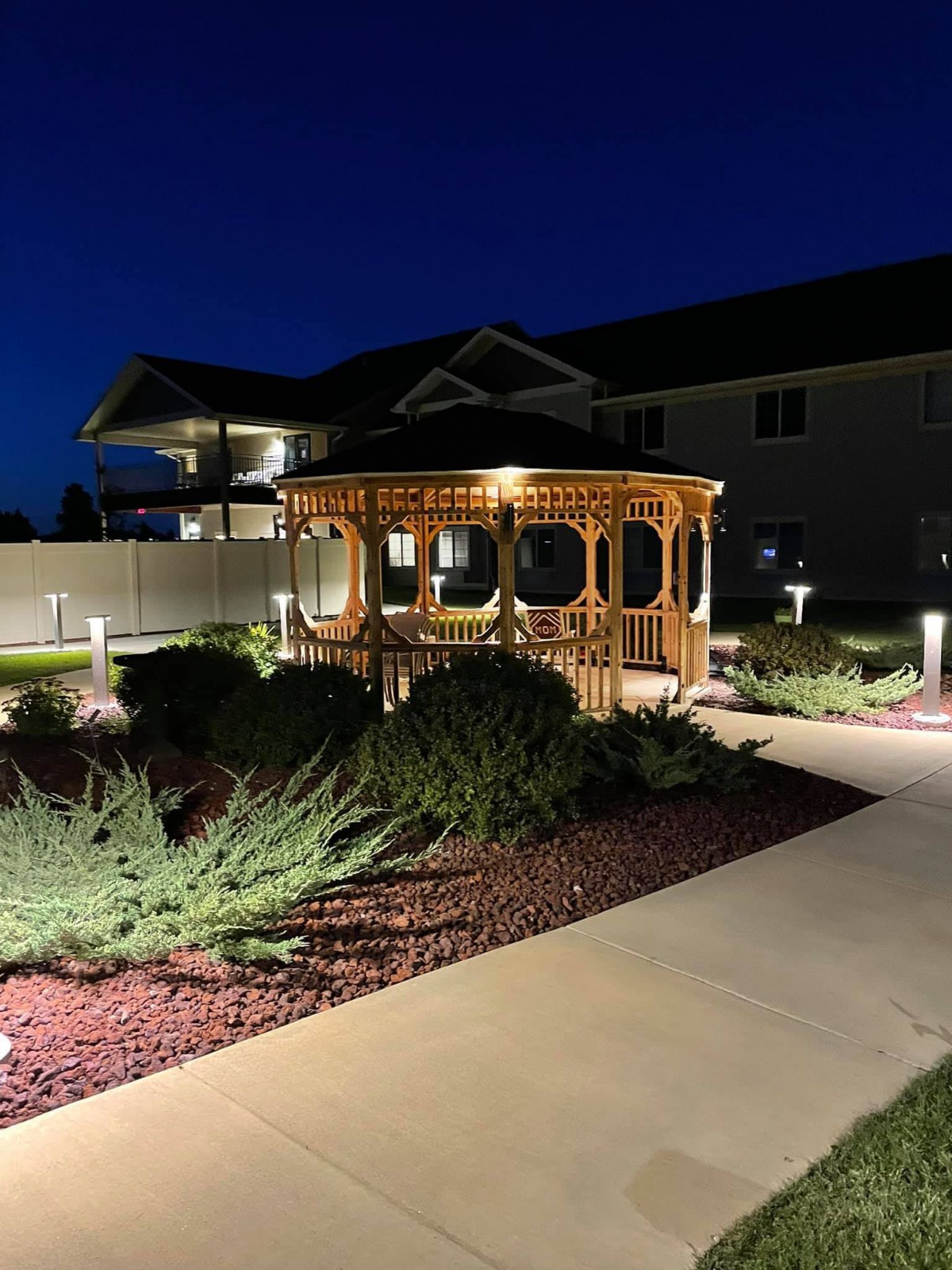 Illuminated gazebo and garden pathway at night.