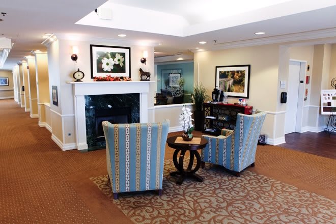 A cozy living room features a fireplace, two striped chairs, and decorative artwork.