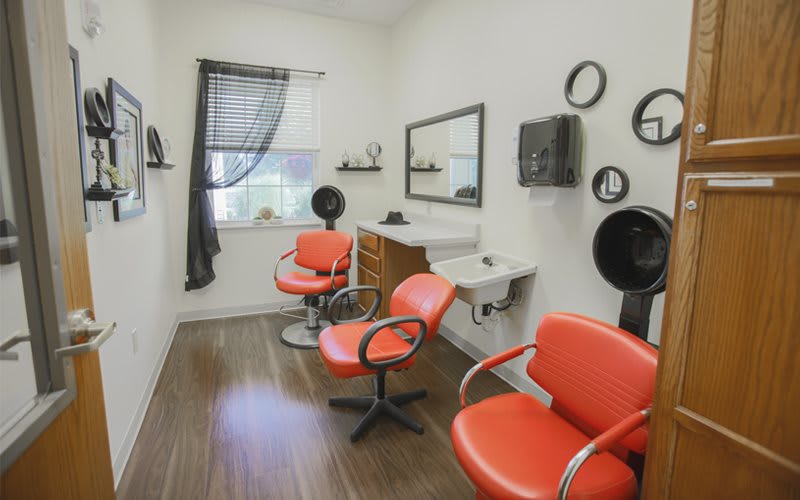 A cozy hair salon with orange chairs and modern decor.