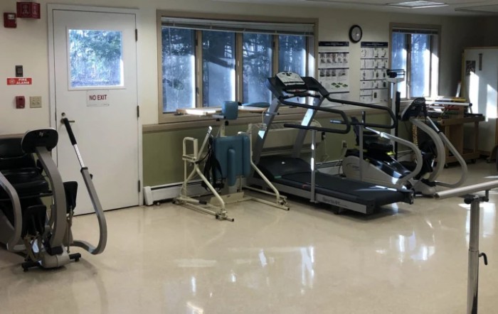 A fitness room equipped with exercise machines including a treadmill and other rehabilitation equipment.