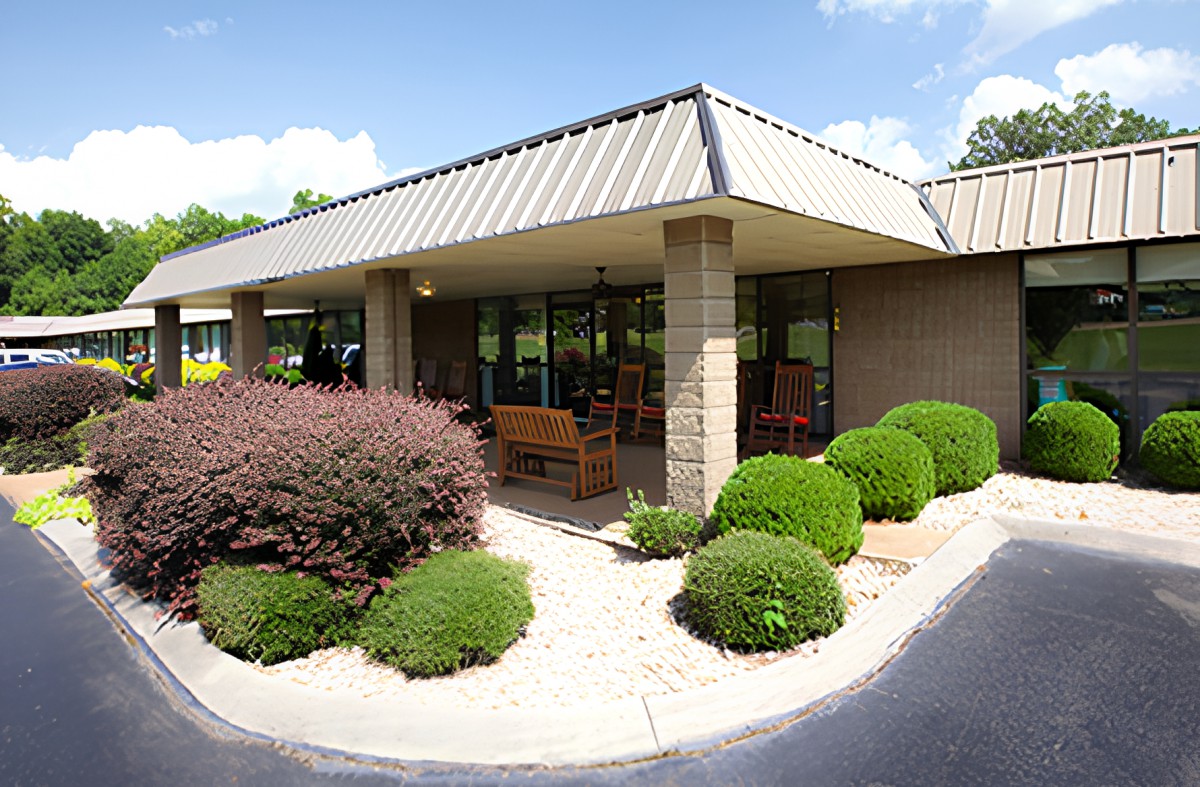 A modern building exterior with neatly trimmed bushes and a covered porch.