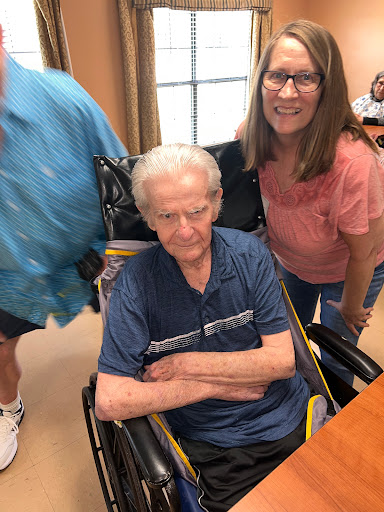 A joyful moment shared with family, capturing an elderly man in a wheelchair surrounded by loved ones.